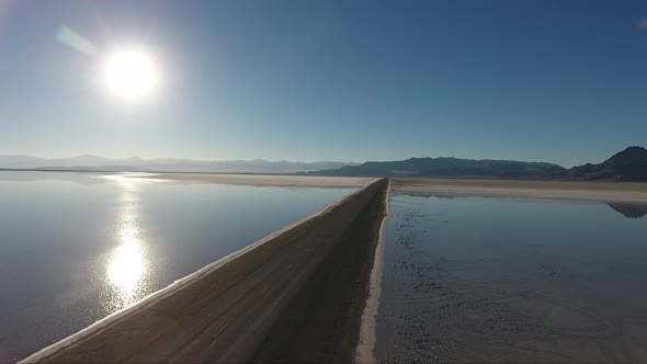 A drone shot flying over the Bonneville Salt Flats shows the Salt Flats causeway dividing the floode