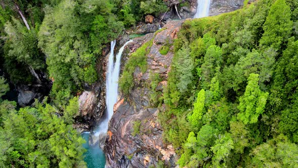 Aerial orbit of the Rio Blanco waterfall surrounded by the forest of Hornopiren National Park, Chile