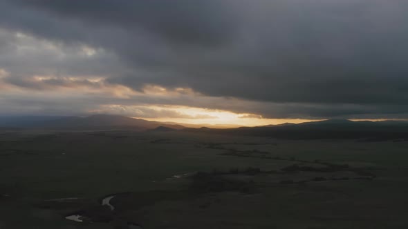 Drone View of a Sunset in a Valley with a River and Mountain Ranges