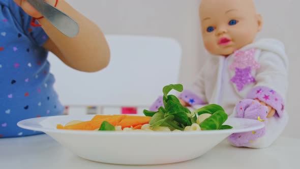 The Child Eats Pasta and Vegetables