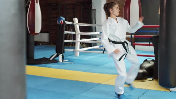 Young Female Kickboxer Practicing with Punching Bag