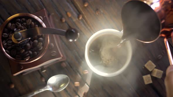 Freshly brewed coffee from cezve is poured into a coffee cup.