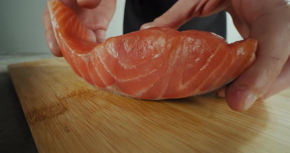 The Chef Puts a Piece of Fish on a Wooden Board for Slicing Close Up Footge