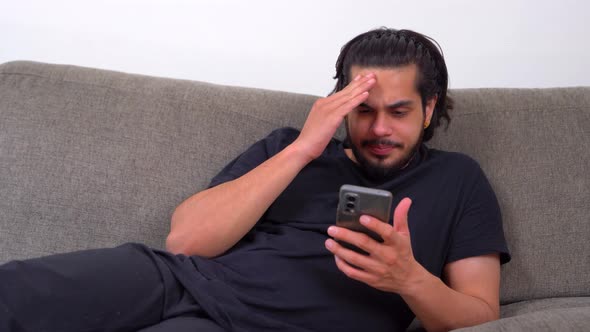 Lazy Indian man scrolling phone at night