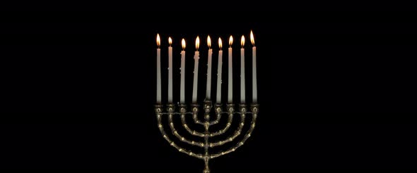 Lit Hanukkah menorah candles burning on a dark background, slow motion