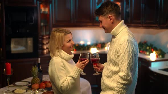 Smiling Couple Clinking Glasses Drinking Wine Standing in Kitchen at Home Indoors