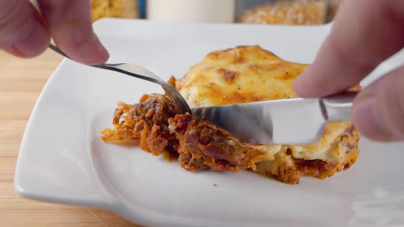 Close Slow Motion Slider Shot of Eating a Fresh Portion of Lasagne on a White Plate with a Knife and