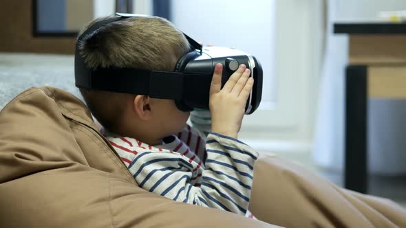 Child Wearing Virtual Reality Glasses and Watching Vr Video at Home at Soft Chair Bag