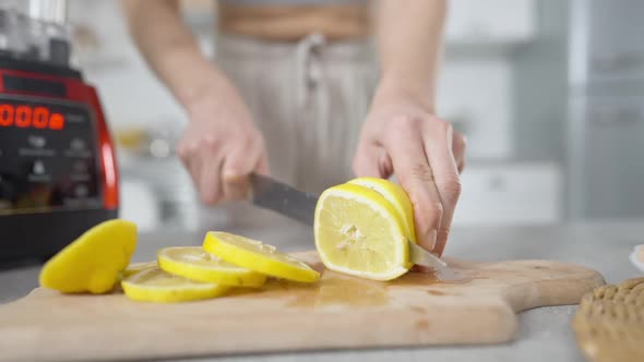 Closeup Female Hands Cutting Vitamin Citrus Lemon with Kitchen Knife on Cutting Board