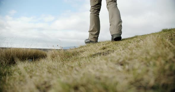 A Close Up View of a Man Legs in Boots Walking on Green Moss and Grass in Iceland