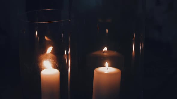 Burning White Candles in Glass Holders on Black Background