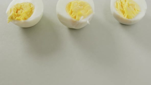 Video of close up of three halves of hard boiled eggs on grey background