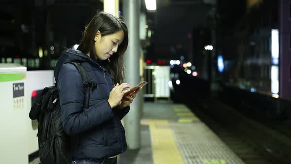 Woman use of the cellphone at train station platform 