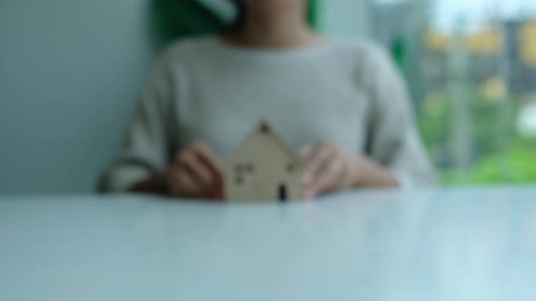 Closeup of a woman holding and showing a wooden house model