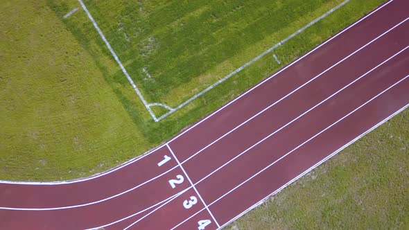 Top view of red running tracks and green grass lawn. Infrastructaure for sports activities.