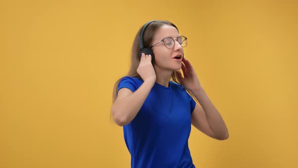 Portrait of Laughing Enthusiastic Woman Dancing Singing Song Earphones Isolated on Orange Studio