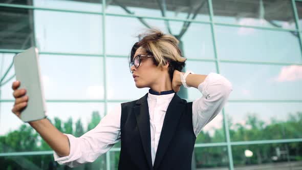 Young Beautiful Businesswoman Looking at Tablet Correcting Hair Business Centre Background