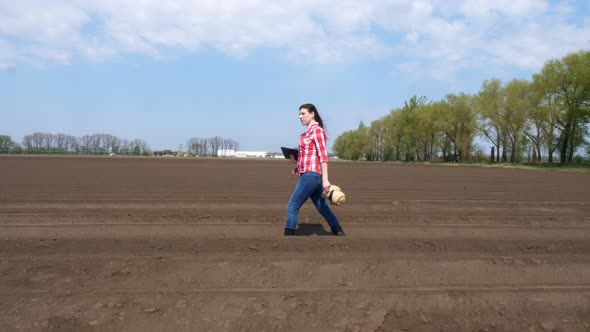 Female Farmer Walks Through Deep Furrow, Between Soil Rows on Field, with Tablet, Testing Quality of