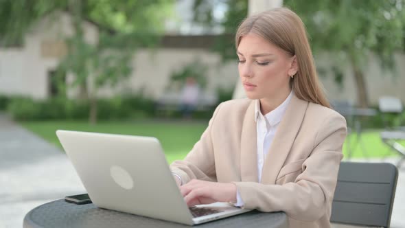 Young Businesswoman with Laptop Looking at Camera in Outdoor Cafe