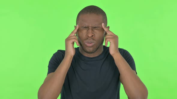 Young African Man with Headache on Green Background