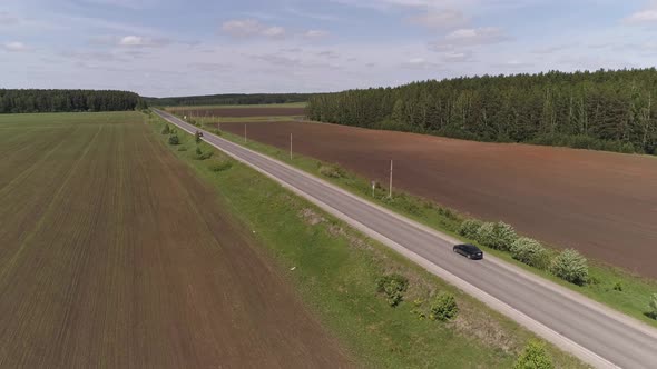 Aerial view of black passenger car driving on a straight asphalt road 03