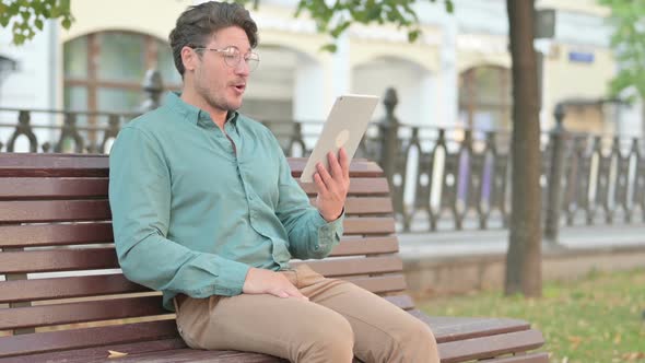 Man Talking on Video Call while Sitting on Bench