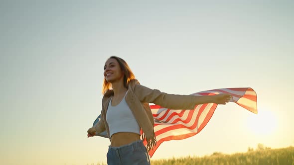 Teenage Girl Proudly Holding American Flag at Field with Golden Sunshine