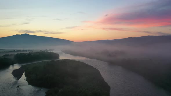 Fog over the river in the mountain valley. Landscape during sunset. View from the air. 