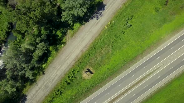 Aerial: Flying Over the Highway and Forest. The Sun Glare Is Visible. View Vertically Down