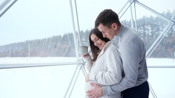 Man Pets Pregnant Woman Belly Enjoying Cup of Tea in Hotel