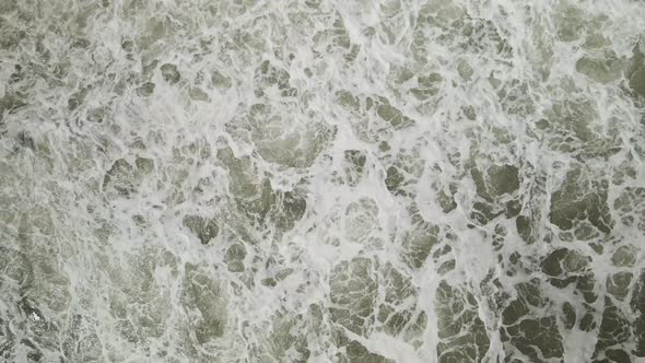 Ascending aerial over waves crashing on beach