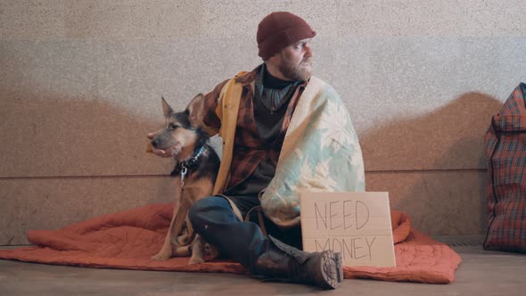 A Poor Man is Petting His Dog While Sitting in the Underpass