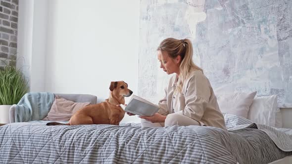 Young Beautiful Woman Reading Book with Small Brown Dachshund Dog