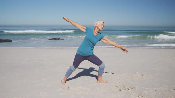 Senior Caucasian woman practising yoga on the beach