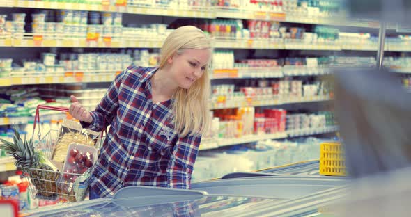 Woman Opening Glass Door of the Fridge and Taking Frozen Food at Supermarket