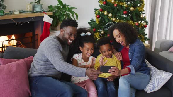 Smiling african american family having video call and gesturing, christmas decorations in background