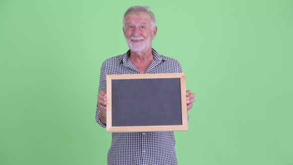 Happy Senior Bearded Man Thinking While Holding Blackboard