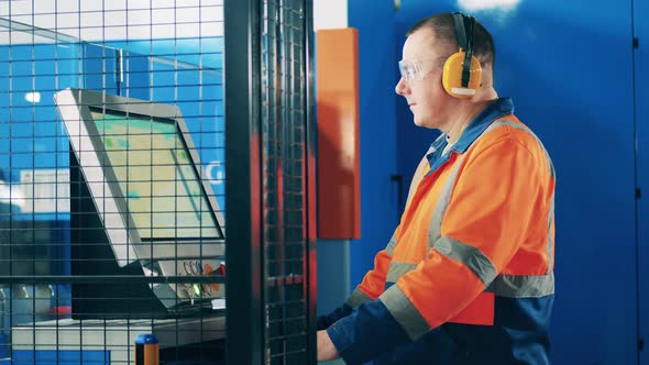 Computerized Machine is Getting Operated By a Factory Worker