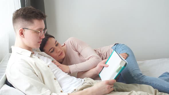 Young Good Looking Couple Enjoing Reading a Book in the Evening.