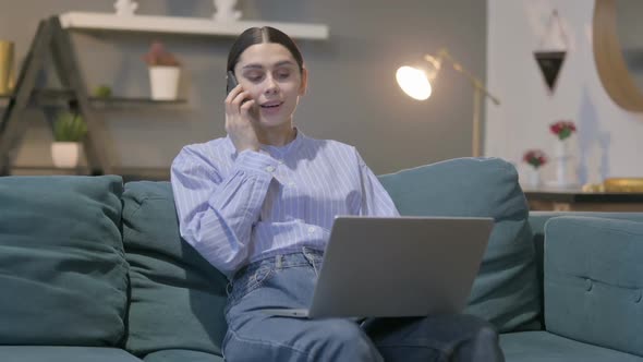 Hispanic Woman with Laptop Talking on Phone on Sofa