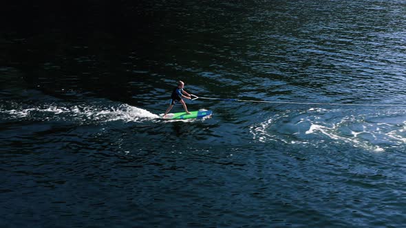 Drone view of kid doing wake board in the sea.