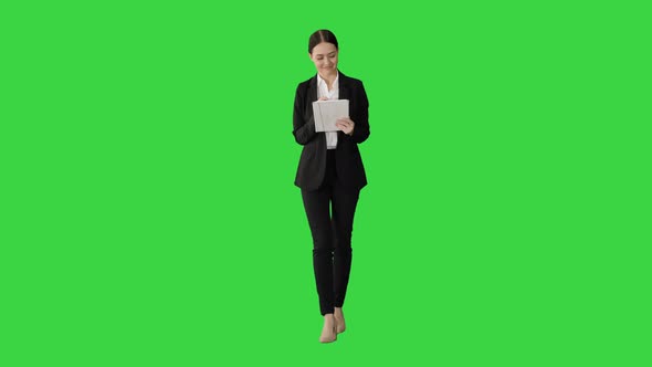 Smiling Businesswoman Using Computer Pad While Walking Towards the Camera on a Green Screen, Chroma