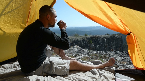 Man drinks from a mug in an camping outdoor