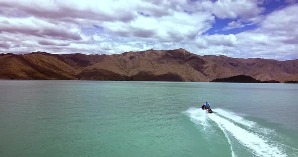 Epic follow shot of a man enjoying riding his jet ski across Lake Benmore, New Zealand's largest art