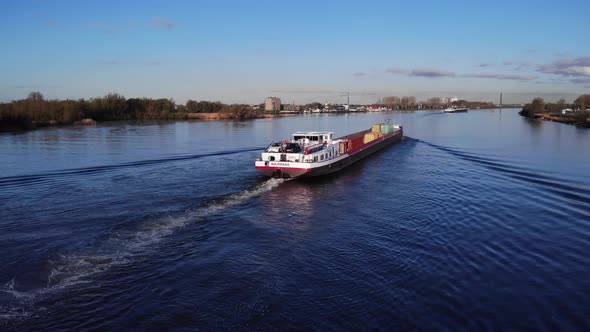 Intermodal Container Vessel Sailing On Peaceful River With Blue Sky In Netherlands. - Aerial Shot