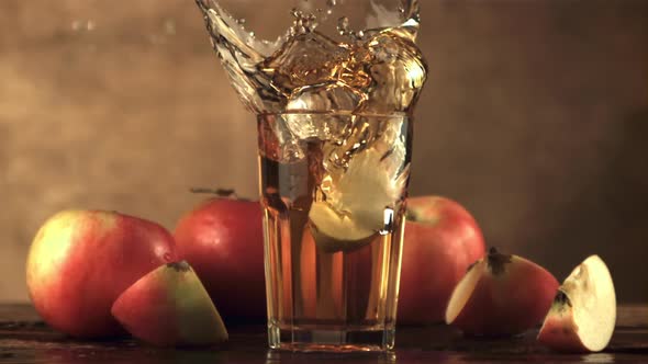 Super Slow Motion in a Glass with Apple Juice Falls a Piece of Apple with Spray