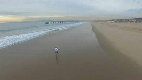 Aerial shot of young man running on the beach.