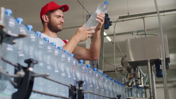 Young Man Worker of Water Factory Checking Quality and Making Inspection in Line Production