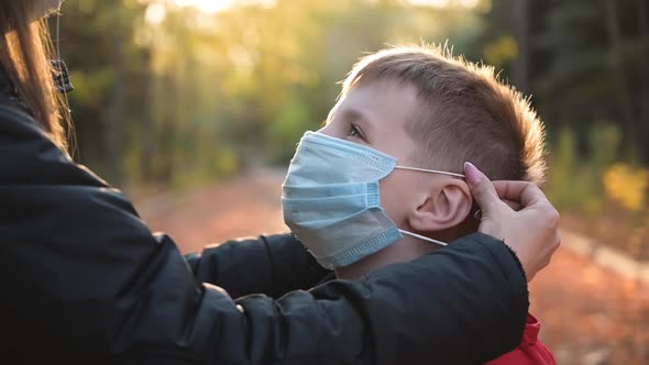 Woman Put Medical Mask on Face of Little Cute Boy and Hugs Him