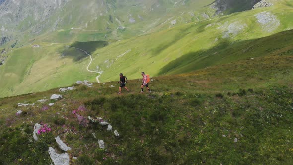 Aerial: couple backpackers hiking on mountain top Summer adventures on the Alps